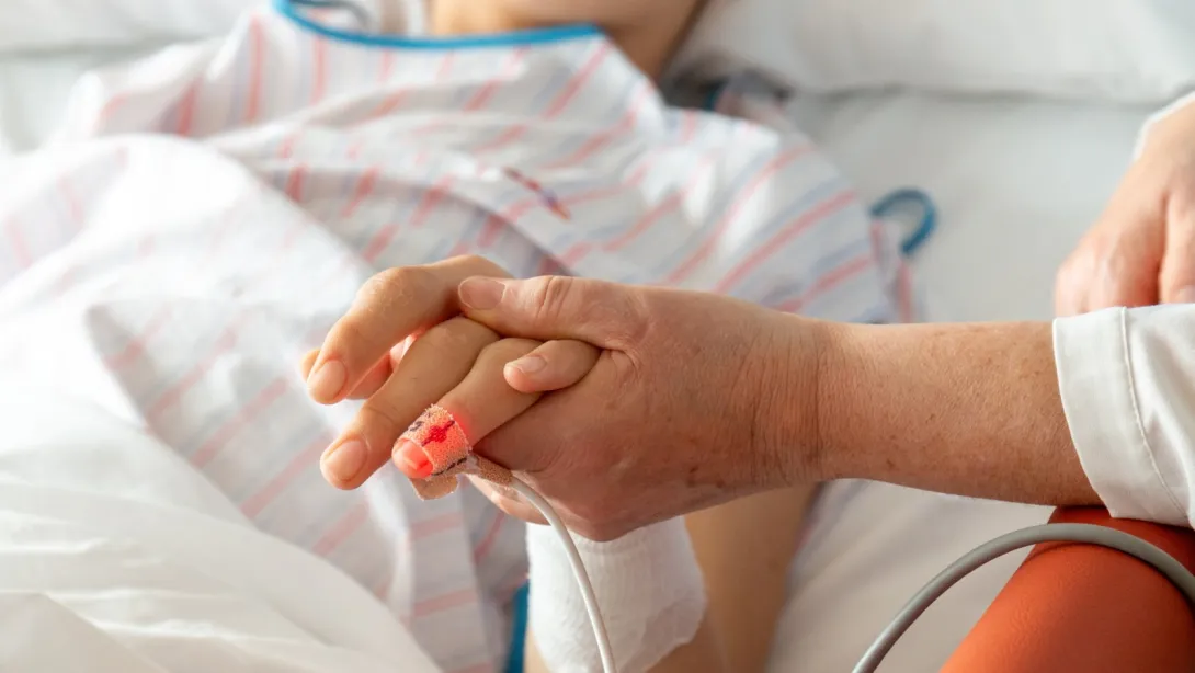 Una persona coge de la mano a un paciente Una persona coge de la mano a un paciente, imagen de detalle, Hospital Sant Joan de Déu