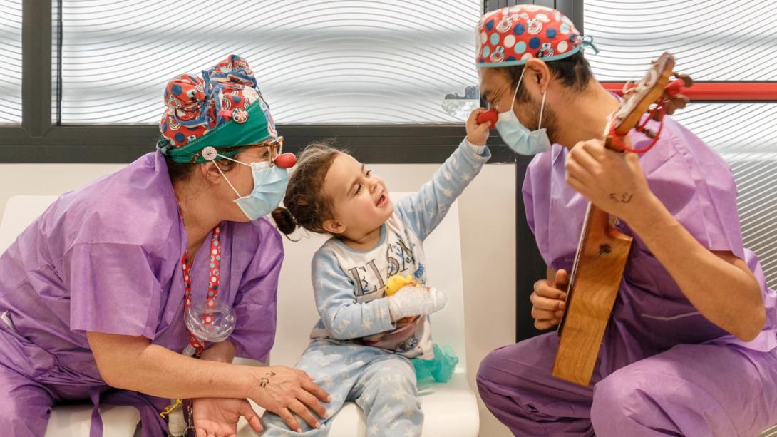 Pallassos jugant amb una pacient en una sala d'espera de l'Hospital Sant Joan de Déu