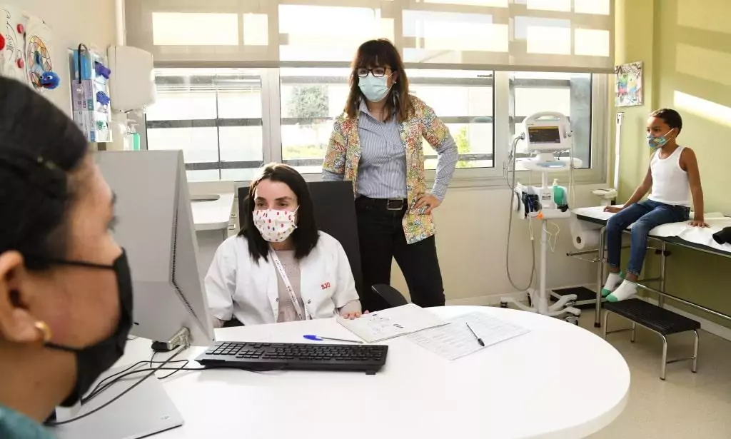 Médico y paciente atienden una familia en consulta Médico y paciente atienden una familia en el Hospital Sant Joan de Déu Barcelona
