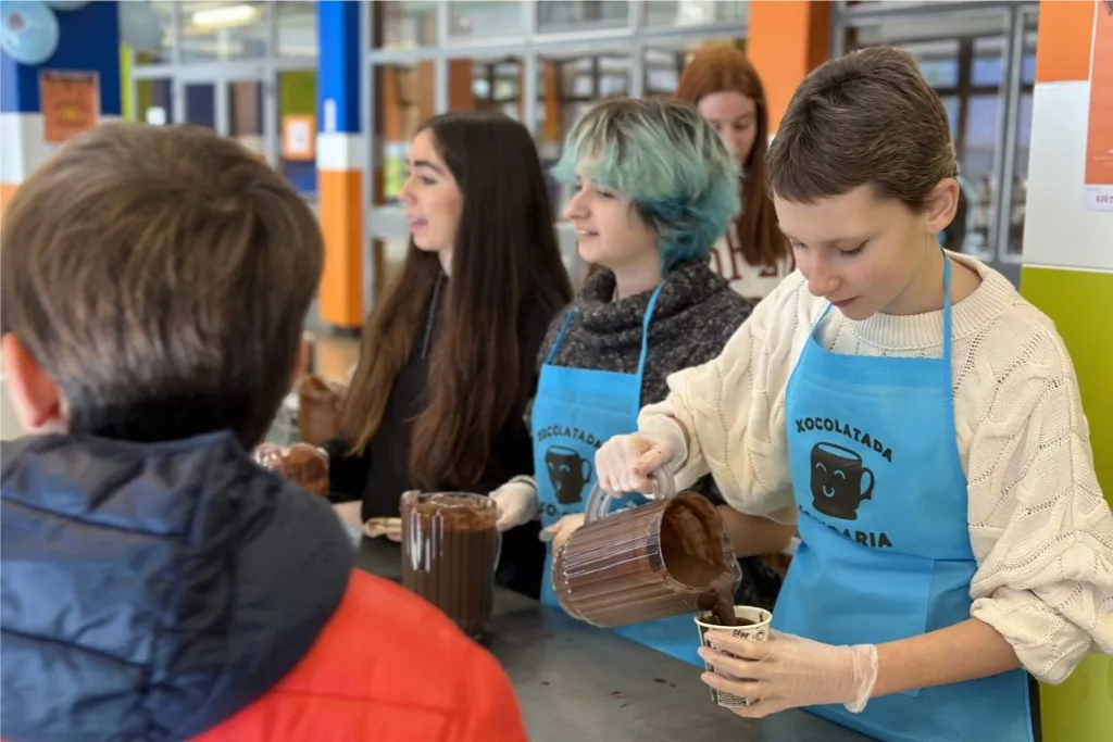 7a edició Xocolatada solidària Alumnes d'un institut servint gots de xocolata desfeta