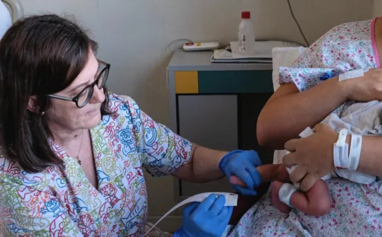 Performing a heel prick test on a newborn