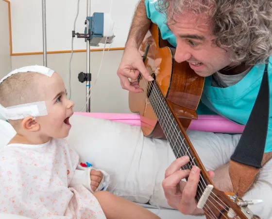 Un pacient rep al musicoterapeuta a l'habitació Un pacient ingressat en un taller de musicoteràpia a l'Hospital Sant Joan de Déu