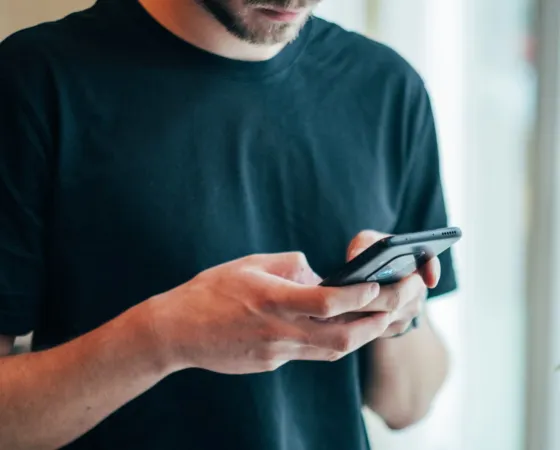 Persona teclejant un dispositiu mòbil Persona enviant un missatge mitjançant un dispositiu mòbil