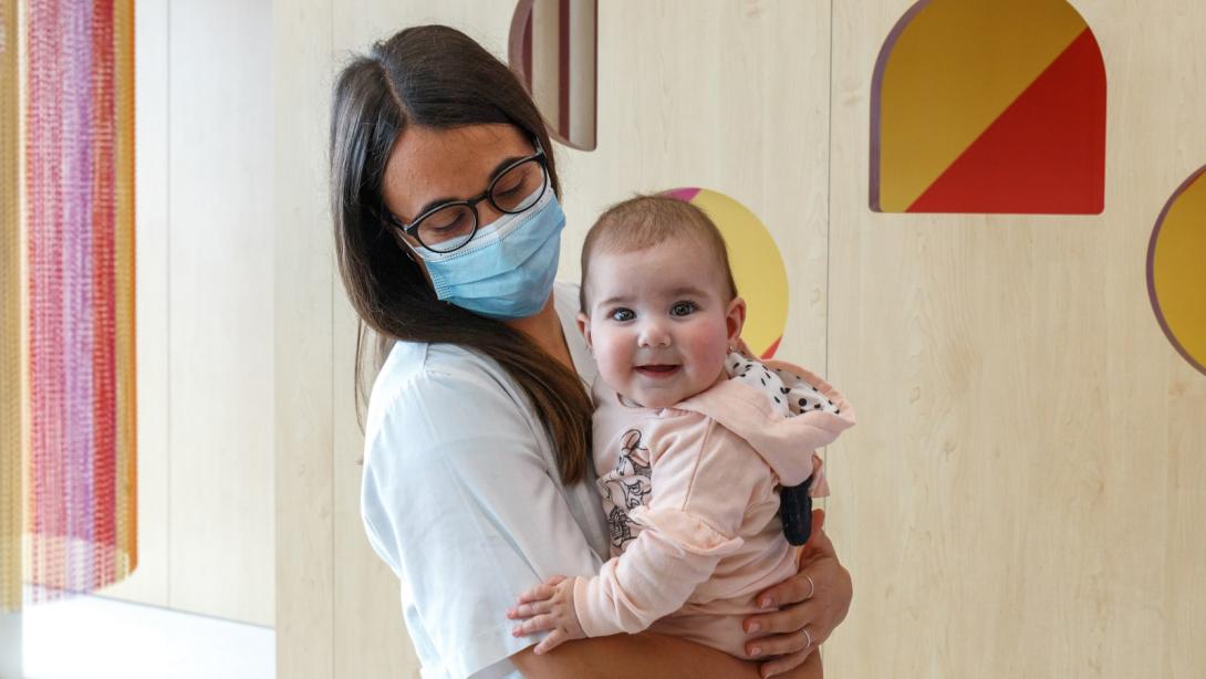 Una niña sonríe en brazos de una profesional del Hospital Sant Joan de Déu Barcelona Paciente con profesional Hospital Sant Joan de Déu Barcelona