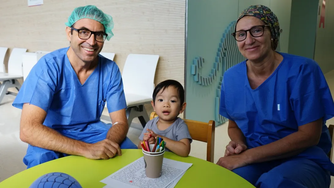 El paciente con el médico y una de las enfermeras que lo han tratado en la UCA Paciente de retinoblastoma con oftalmólogo pediátrico y enfermera