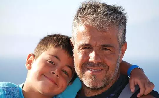 Un niño posa en una fotografía con su padre