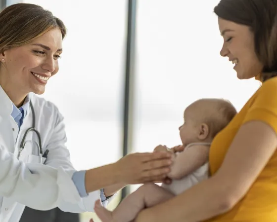 Doctora examina a bebé sostenido por su madre Doctora examina a bebé sostenido por su madre - Hospital Sant Joan de Déu Barcelona